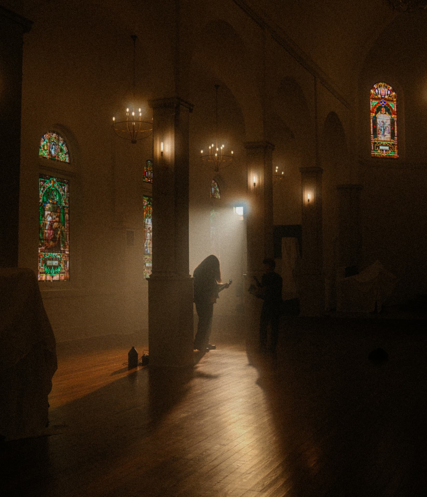 Silhouetted band member in a hazy chapel aisle