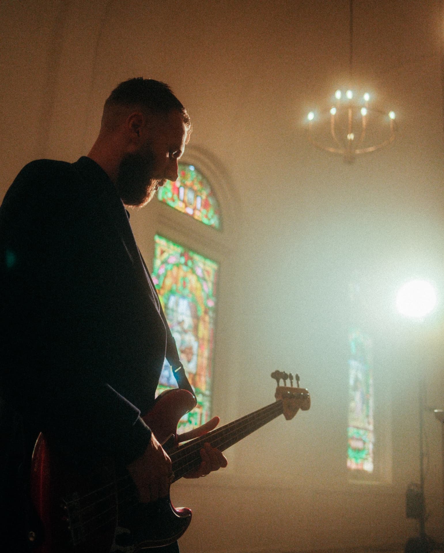 Bassist playing before a stained glass window