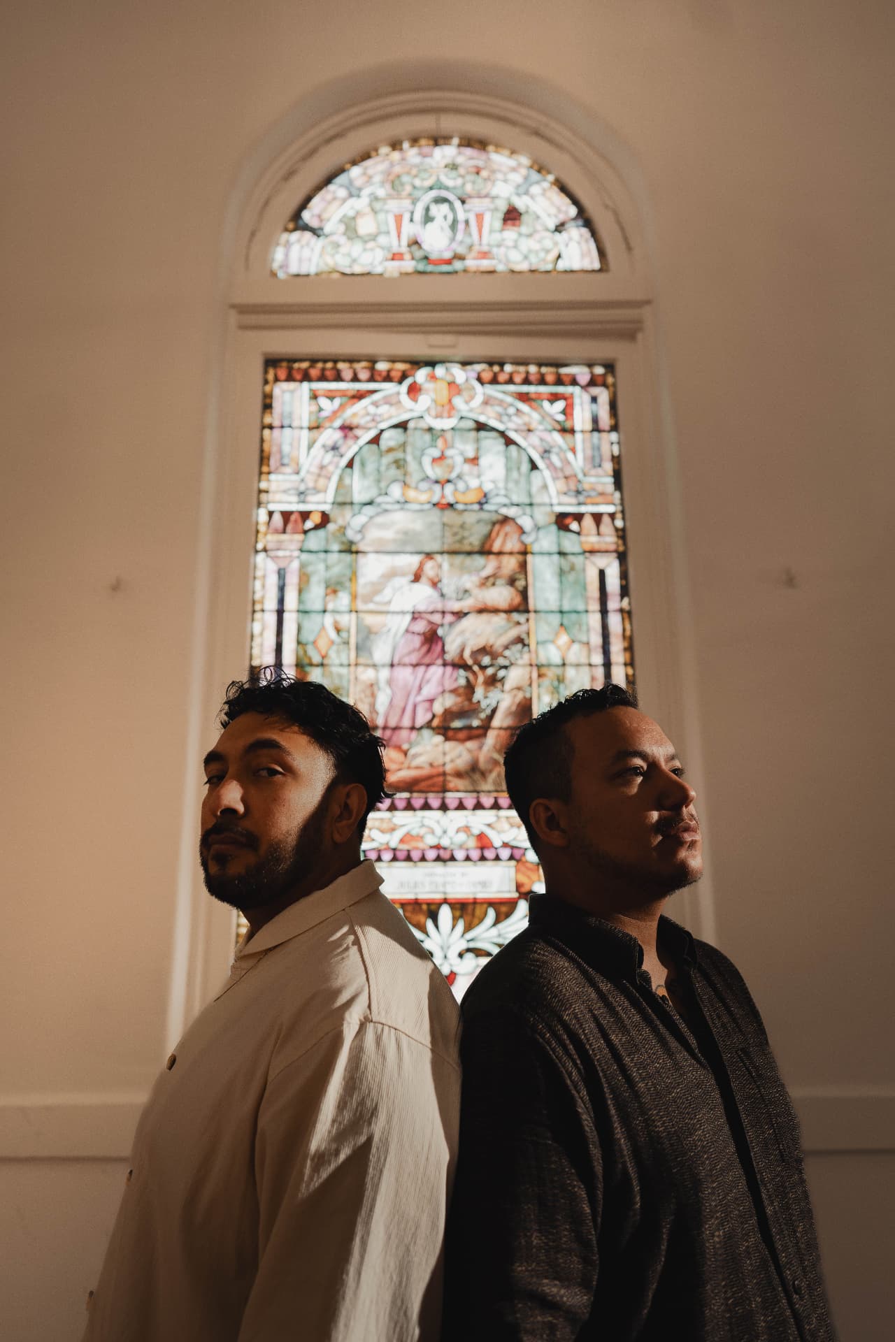 Scroll Eater back to back in front of a stained glass window